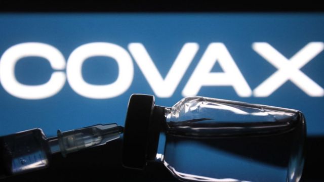 Une seringue médicale et un flacon devant le mot COVAX sont visibles sur cette photo illustrative et créative