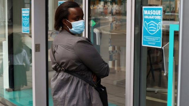 A woman wearing a mask in Antwerp enters a shop