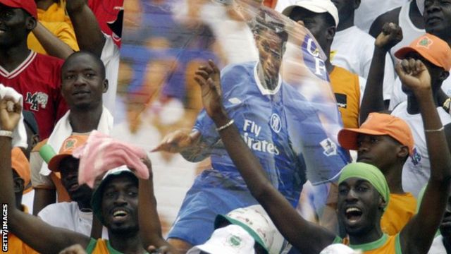 Jubilant Ivory Coast fans hold up a poster of Didier Drogba in Chelsea kit