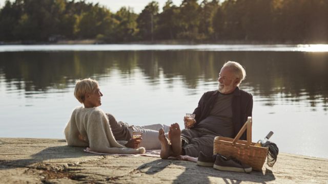 Una pareja mayor tomando vino a la orilla de un lago