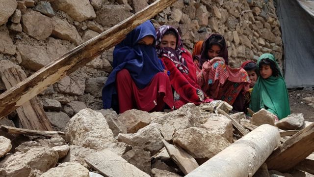 Girls sitting among the rubble