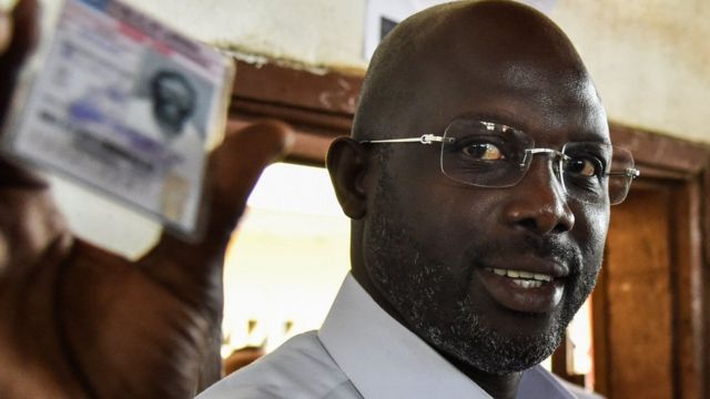 Former football star George Weah shows his voting card at a polling station in Monrovia on October 10, 2017