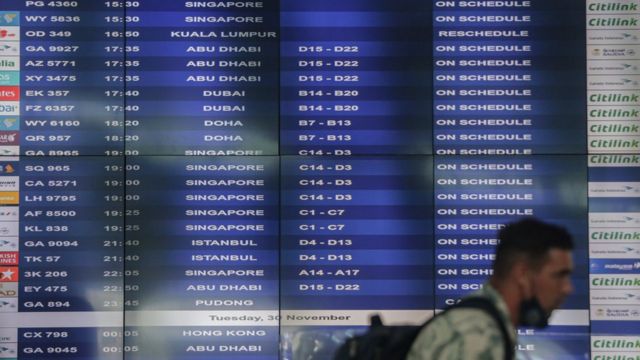 Warga Negara Asing (WNA) berjalan melintasi papan jadwal informasi penerbangan internasional di Terminal 3 Bandara Internasional Soekarno-Hatta, Tangerang, Banten, Senin (29/11).