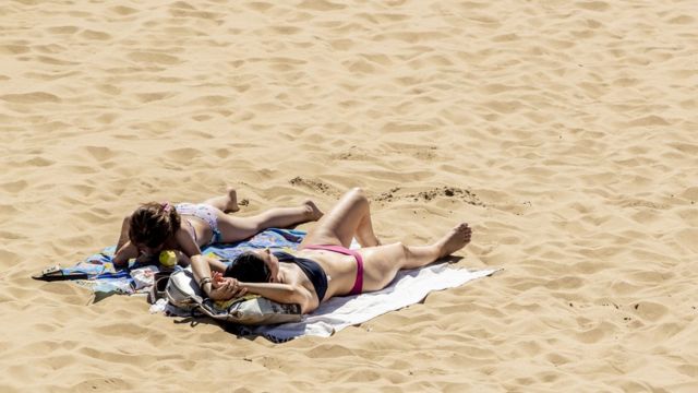 Mujeres broncéandose sobre la arena