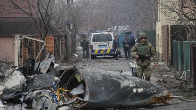 Um soldado passa pelos destroços de um avião militar que foi abatido durante a noite em Kiev, Ucrânia, 25 de fevereiro de 2022
