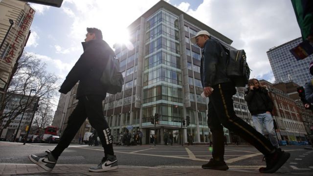 Pedestres caminham em frente à sede da Cambridge Analytica em Londres