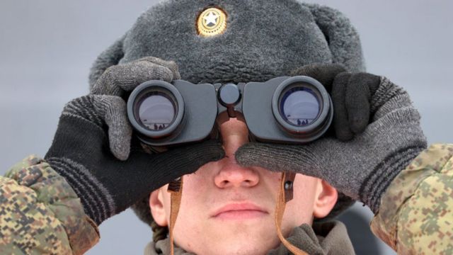 Un militaire russe regarde à travers des jumelles
