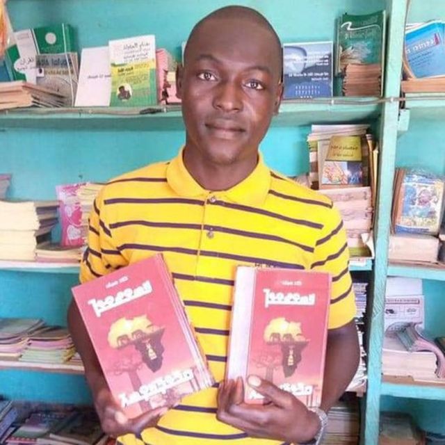 Al-amine Berete, Traductologue (arabe, Français et N'ko) et président de l'Association pour le Progrès et l'Epanouissement de N'ko en Guinée (APENG) tient deux copies du dictionnaire N'ko