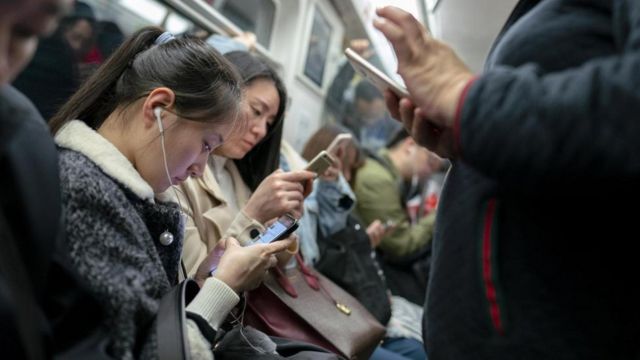 Chineses olham para seus celulares no metrô