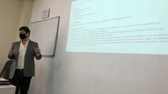 Professor Carlos Quiroga em frente a uma imagem de um currículo