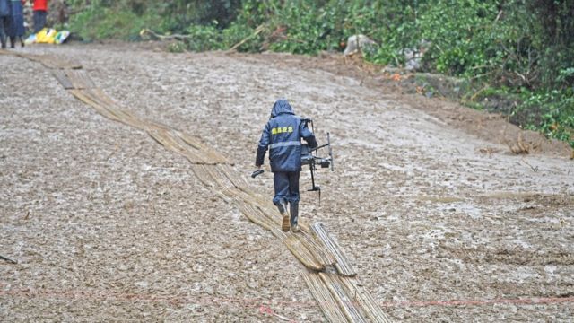 广西梧州藤县中国东航MU5735航班坠落事故坠落现场无人机操作人员在铺上竹子的泥泞路面上行进（新华社图片23/3/2022）