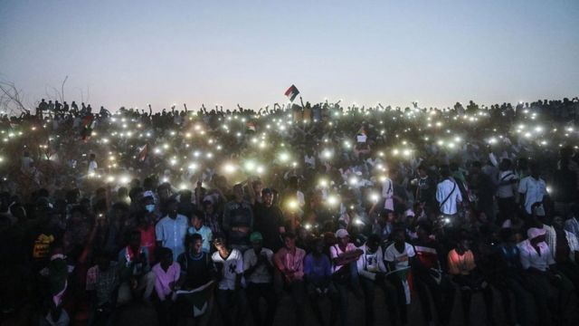 Pessoas com celulares erguidos em protesto no Sudão