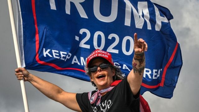 أحد مؤيدي الرئيس الأمريكي السابق دونالد ترامب يحمل علم ترامب 2020 بالقرب من نادي مار إيه لاغو في بالم بيتش، فلوريدا، في 1 أبريل 2023.