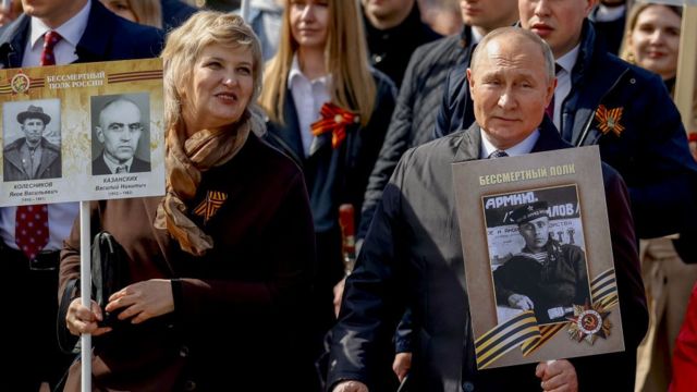 الرئيس الروسي فلاديمير بوتين (إلى اليمين) يحمل صورة لوالده بعد موكب يوم النصر في الساحة الحمراء، 9 مايو 2022 ، في موسكو، روسيا