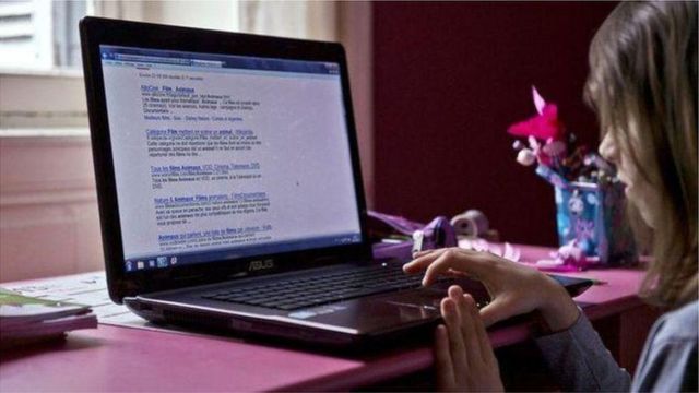 Bé gái ngồi dùng máy tính xách tay
