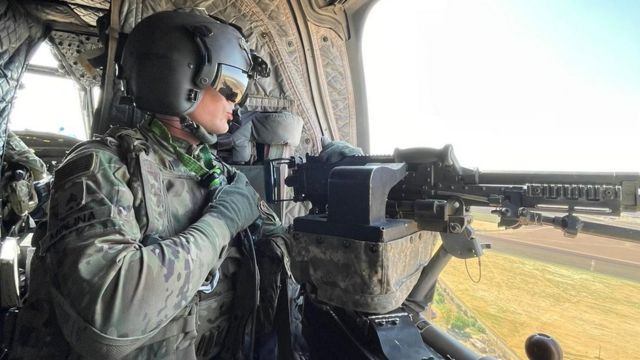 جندي أمريكي يحمل مدفع رشاش على متن طائرة هليكوبتر