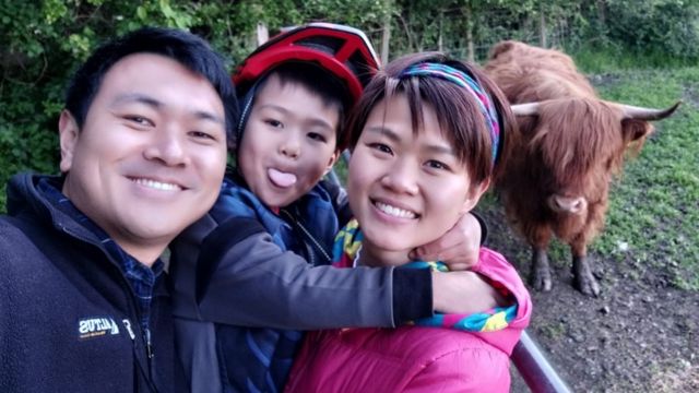 Yau and his family in front of a highland cow
