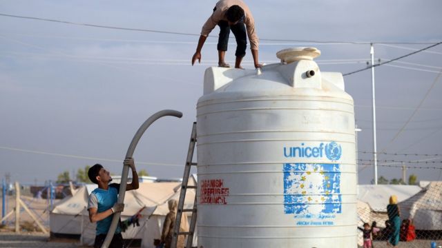 इरबिल के पास बनाए गए संयुक्त राष्ट्र के शरणार्थी शिविर में पानी की टंकी लगाते कर्मचारी.