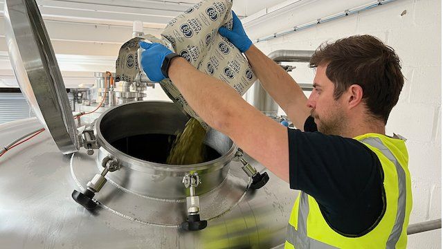 Man pours hops into a vat during the brewing process