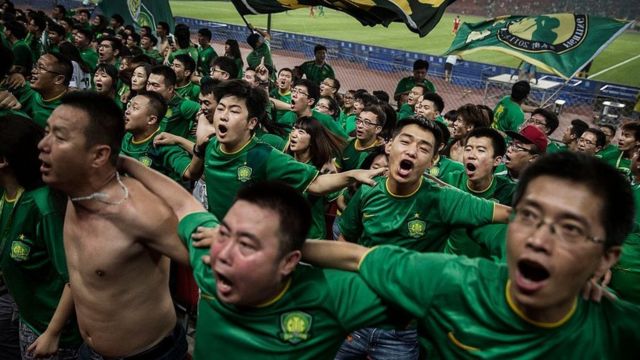 中超比赛中，北京国安球迷背对着球场载歌载舞。