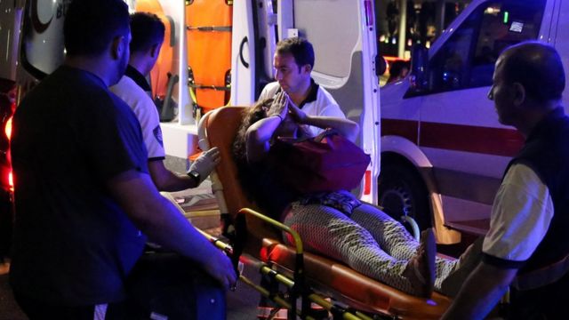 Una mujer herida se cubre el rostro mientras es trasladada por paramédicos tras el atentado en el aeropuerto de Estambul.