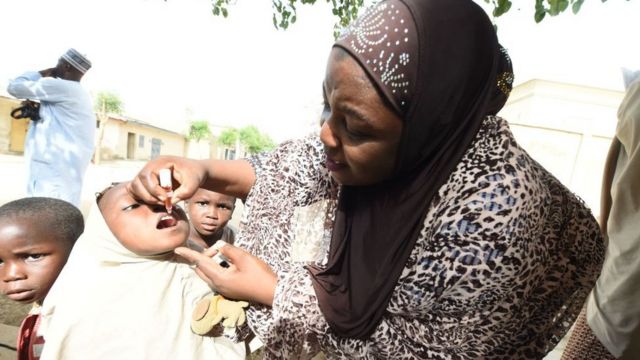 UNICEF health consultant Hadiza Waya (R) tries to immunise a child during vaccination campaign against polio at Hotoro-Kudu, Nassarawa district of Kano in northwest Nigeria, on April 22, 2017