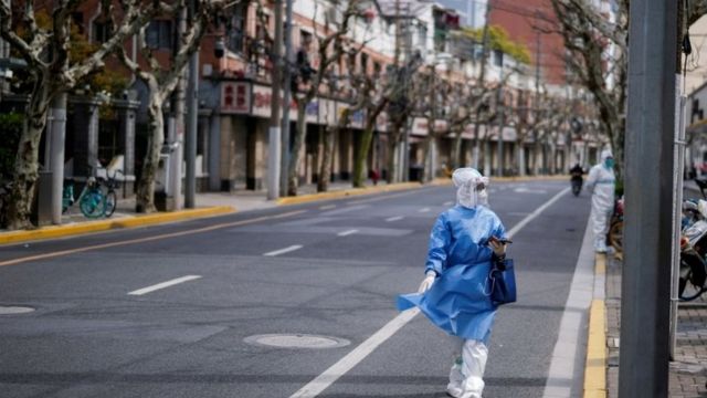 A worker in a protective suit keeps watch on a street, as the second stage of a two-stage lockdown to curb the spread of the coronavirus disease (COVID-19) begins in Shanghai, China April 1, 2022.