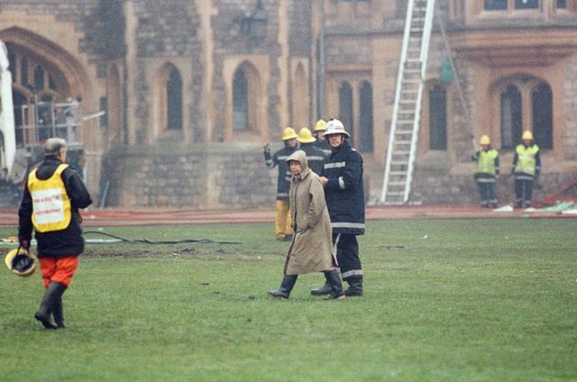 The Queen is escorted by the chief fire officer around the grounds of Windsor Castle as fire fighters battle a fire, 20 November 1992.