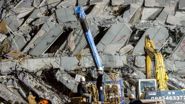 Rescue workers inspect the scene of a collapsed building in the southern Taiwanese city of Tainan following a strong 6.4-magnitude earthquake that struck early on February 6