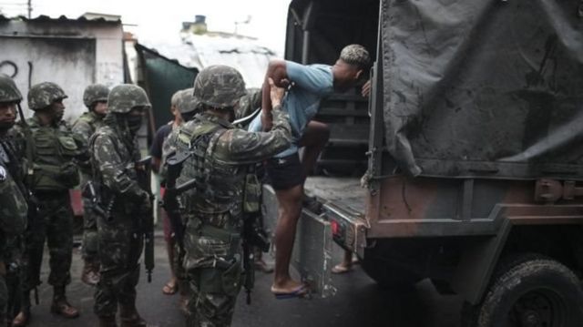 Homem é colocado em caminhão do Exército