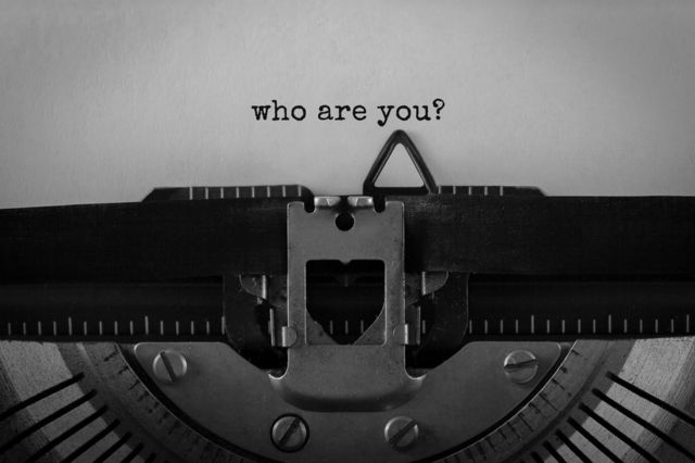 Máquina de escribir y "¿Quién eres tú?" escrito en un papel.
