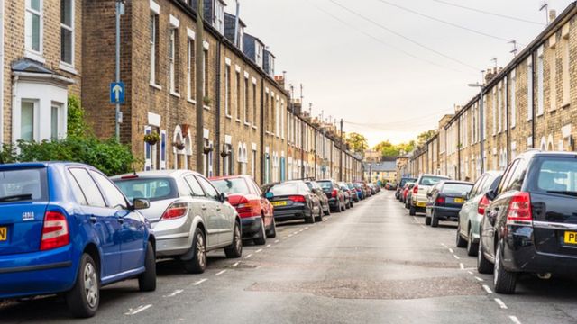Street lined with terraced houses and cars parked in bays outside
