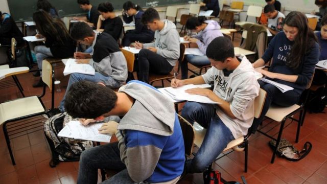 Estudantes fazendo prova numa sala de aula
