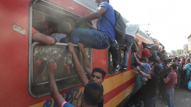People attempting to climb into and onto a full train