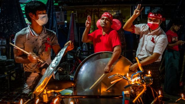 People bang their utensils and do the three-finger salute in a Yangon market on 5 February 2021
