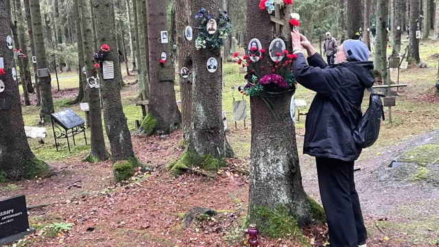 A woman puts flowers on a tree in the woods outside St Petersburg where tens of thousands of Stalin's victims are buried