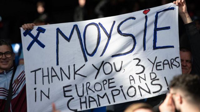 A fan holds a sign saying, 'Moyesie, thank you, three years in Europe and champions!'