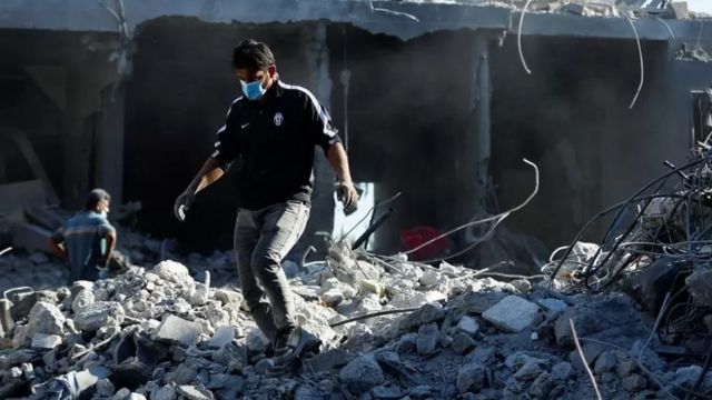 Homem caminha sobre escombros após bombardeios em Gaza