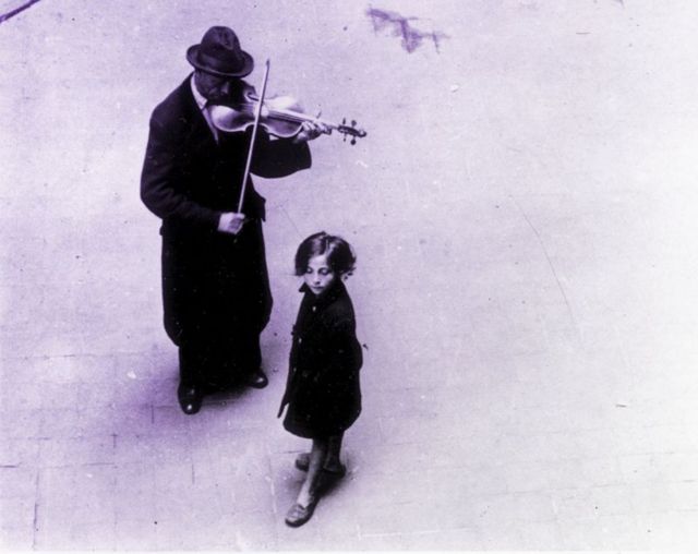 Músico e criança em rua da Hungria