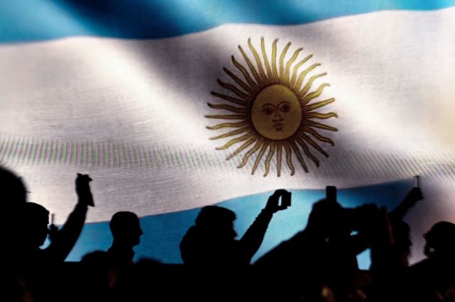 Argentinos delante de la bandera de su país.