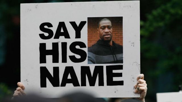 Un manifestant tenant une pancarte avec la photo de George Floyd