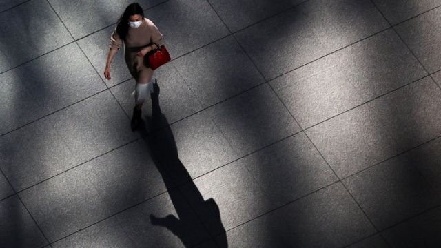 Tokyo'da maskeli bir kadın yürüyor