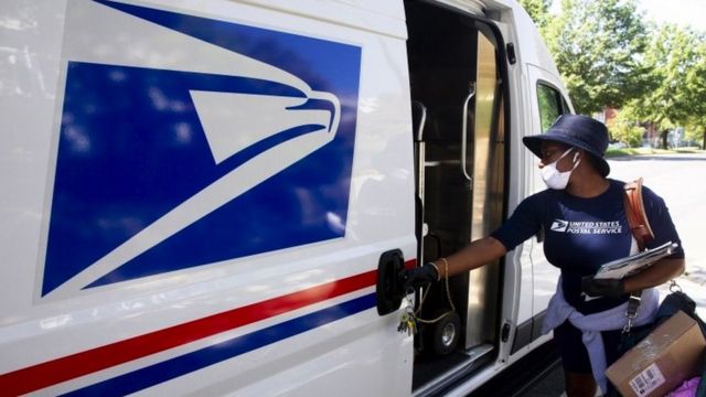 A woman from the US Postal Service closes a van door