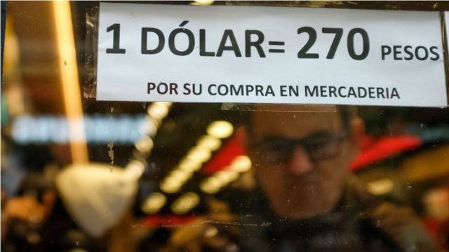 Un cartel que dice "1 dólar = 270 peses por su compra en mercadería"