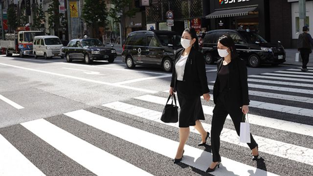 Trabalhadoras japonesas caminham em rua de Tóquio