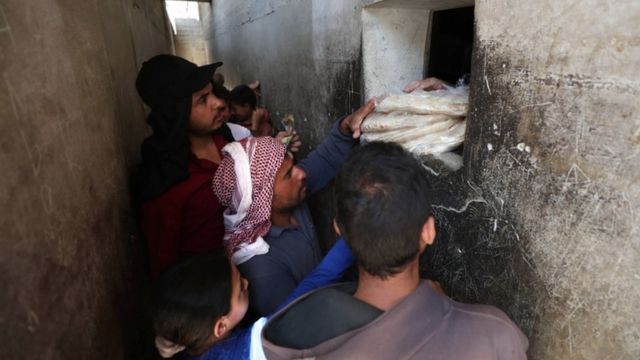 سوريون في إدلب يقفون أمام فرن للخبر