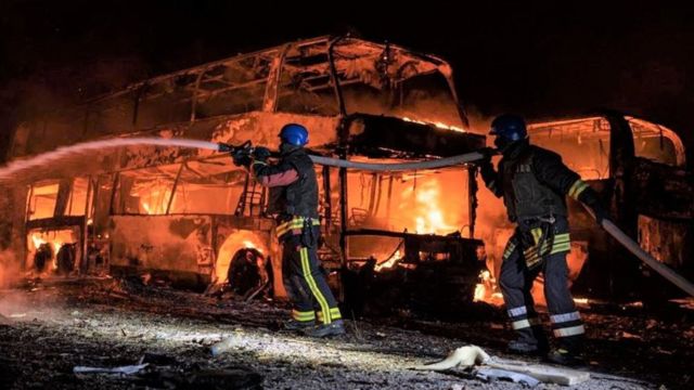 عمال أطفاء يعملون على إخماد النيران في باص طاله القصف في كييف