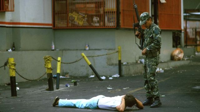 Militar armado frente a civil tumbado en el suelo en protestas desencadenadas en 1989.