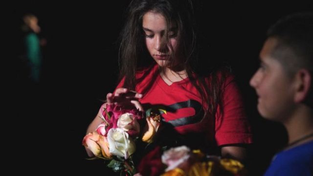 Uma jovem segura flores do lado de fora do Centro Cívico Willie de Leon, para lamentar o massacre em Uvalde, Texas, em 24 de maio de 2022.
