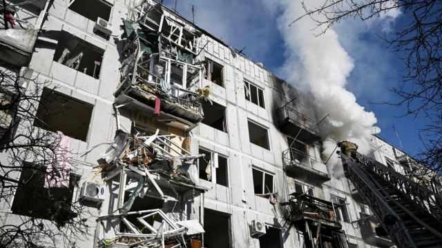 Các nhân viên cứu hỏa làm việc trên một tòa nhà sau vụ đánh bom vào thị trấn Chuguiv, miền đông Ukraine vào ngày 24 tháng 2 năm 2022.
